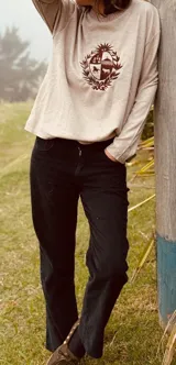 Sweater de punto color crema, de corte holgado y manga larga, con cuello redondo. Presenta un escudo bordado en azul en el centro del frente.