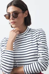 Polera de cuello alto con diseño de rayas horizontales en color azul marino sobre fondo blanco, confeccionada en tejido de punto con mangas largas.