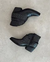 Botines negros de cuero con textura de piel de serpiente, punta fina, cierre lateral y apliques de tachas plateadas.