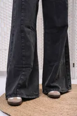 Pantalón wide leg de denim negro desgastado, de tiro medio con doble botón y corte amplio en las piernas con costuras frontales.