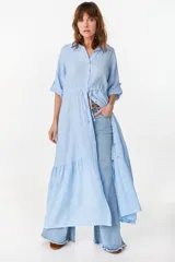 Vestido camisero largo de lino italiano color celeste, de corte relajado, con mangas caídas, jareta ajustable en la cintura, cierre frontal de botones y bajo con volado fruncido.