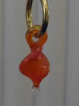 Aros tipo argolla de acero quirúrgico con dije colgante de cristal de Murano en forma de espiral color naranja.