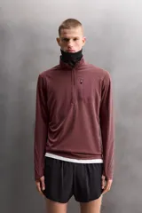 Sudadera técnica color vino tinto, de manga larga, con cuello subido y cierre frontal de cremallera. Presenta un bolsillo frontal con cierre de cremallera oculta en costura y detalle de logo estampado. El tejido tiene estructura waffle en el interior.
