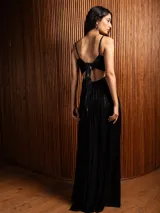 Vestido largo metalizado color negro, con tirantes finos, escote en V, falda plisada y espalda abierta con nudo.