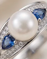 Anillo de plata 925 con una perla central y circonias azules y transparentes en los laterales.
