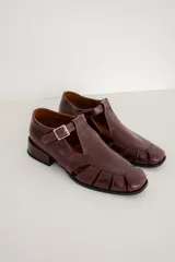 Sandalias Mary Jane de cuero color bordeaux, con diseño de tiras cruzadas, puntera cuadrada y taco bajo.