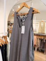 Mono largo de lino color beige, con escote en V, tirantes anchos, bolsillos laterales y silueta holgada. Cuenta con espalda ajustable mediante lazos.