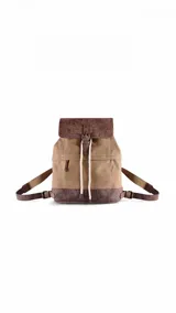 Mochila de estilo casual confeccionada en tela canvas color beige, con detalles en cuero sintético marrón envejecido en la tapa, base y correas. Presenta cierre con solapa, hebilla decorativa, cordones ajustables y bolsillo frontal con cierre.