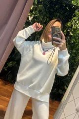 Conjunto de dos piezas compuesto por un buzo de cuello alto y mangas largas con puños, y un pantalón palazzo de corte holgado. Ambas prendas están confeccionadas en tejido de punto suave de color blanco.