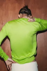 Jersey polo de punto fino color verde lima, confeccionado con lana. Presenta cuello polo, manga larga y botones delanteros.