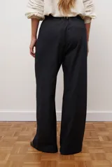 Pantalon de corte recto y pierna ancha, confeccionado en tejido tipo denim oscuro. Presenta tiro alto, cintura con cierre frontal y bolsillos laterales funcionales.