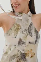 Vestido corto con estampado floral en tonos beige, verde y marrón, con cuello halter y lazo.