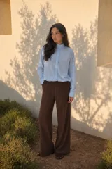 Camisa celeste de silueta relajada, con cuello alto abotonado, cartera frontal con botones y mangas largas con puños amplios.