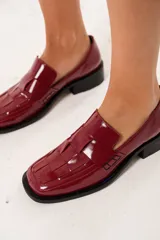 Mocasín de cuero charol color cereza con diseño enrejillado en la capellada, horma cuadrada, plataforma delantera y taco bajo.