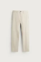 Pantalón chino beige de corte slim fit, confeccionado con tejido elástico. Cuenta con bolsillos frontales, bolsillos traseros de vivo con botón y cierre frontal con cremallera y botón.