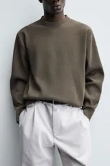 Jersey de punto con textura, corte relajado, cuello redondo y manga larga con acabados en rib.