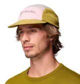 Gorra Columbia Wingmark de cinco paneles en combinación de colores rosado, gris, verde militar y mostaza, con visera curva, paneles laterales de malla y logo bordado en el frente.