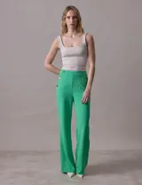 Pantalón naranja de crepe elastizado, corte recto, con bolsillos delanteros y apliques de botones metálicos.