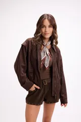 Campera de gamuza color beige con diseño de calados florales en hombros y espalda, cierre frontal y cuello camisero. Presenta un corte relajado y textura suave.