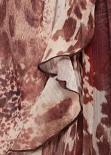 Vestido corto de gasa con estampado animal print en tonos marrones. Presenta cuello redondo con detalle fruncido, mangas largas con puños elásticos, volantes decorativos en el pecho y falda con volado en el ruedo. Incluye forro interior.