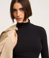 Suéter de cuello alto y manga larga, confeccionado en algodón con elastano. Presenta un diseño básico y ajustado al cuerpo.