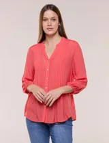 Blusa de silueta suelta de textura liviana, color salmón, con escote en V y cuello mao. Cuenta con acceso frontal mediante abotonadura completa, detalle de alforzas verticales en el pecho, mangas tres cuartos con galón calado tipo puntilla y puños elastizados, y ruedo recto.