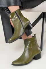 Bota corta de cuero color chocolate, con taco cuadrado y hebilla metálica decorativa en el lateral. Presenta un diseño clásico con punta redondeada.