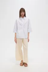 Blusa de algodón a rayas verticales celestes y blancas, holgada, con cuello camisero y mangas 3/4.