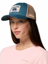 Gorro trucker Columbia de color verde azulado y beige, con paneles de malla trasera y un parche frontal estampado con un oso y la marca.