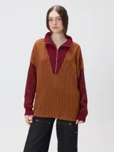 Pullover de tejido acanalado grueso con diseño bicolor en tonos marrón y bordó. Presenta cuello alto con cierre frontal, mangas largas y corte holgado.