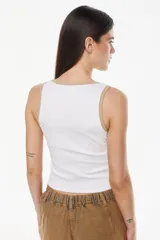 Musculosa de algodón color blanco con ribetes en tono tostado en el escote y las sisas, con detalle de bordado en el bajo.