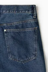 Jean de corte baggy confeccionado en denim de algodón rígido, con diseño de cinco bolsillos, tiro bajo y piernas amplias de silueta redondeada.