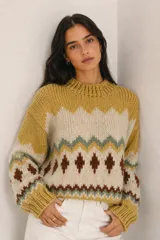Sweater de lana merino color beige, con diseño tejido de punto jacquard estilo nórdico en tonos marrón, negro, blanco y lila en el pecho y las mangas. Cuenta con cuello redondo, puños y dobladillo acanalados.