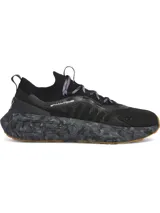 Championes de running Under Armour modelo Phantom 4 Camo, con diseño de corte bajo y estructura tipo calcetín. Presentan capellada de tejido técnico negro, entresuela con amortiguación UA HOVR+ con estampado de camuflaje en tonos grises y suela de goma color caramelo.