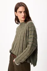 Sweater de punto con diseño de rayas verticales en relieve y textura trenzada, color terracota y beige. Presenta cuello redondo, corte holgado y diseño cropped.