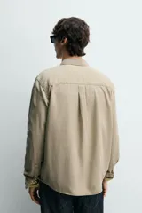 Camisa de corte regular fit en color azul, confeccionada en mezcla de lyocell y algodón, con cuello camisero, manga larga con puños abotonados, cierre frontal con botones y un bolsillo aplicado en el pecho.