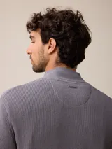 Cardigan de punto gris con cierre frontal completo, cuello tipo mao y puños acanalados. Presenta un pequeño logo bordado en el pecho y detalles en contraste en el interior del cuello y puños.
