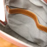 Mochila de cuero color suela con diseño compacto y redondeado. Cuenta con cierre superior, asa superior para llevar a mano y correas ajustables para usar en formato mochila. Presenta el logo de la marca grabado en la parte frontal.