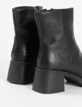 Bota de caña media en color negro, con diseño minimalista, taco cuadrado sólido y plataforma delantera.