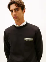 Buzo de cuello redondo Tommy Hilfiger de color negro, confeccionado en tejido interlock técnico de algodón y poliéster. Presenta corte regular, puños y bajo de punto canalé, con un parche bordado del logo de la marca en el pecho y la bandera distintiva bordada en el puño.