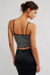 Top corto sin costuras de tejido acanalado y texturado color marfil, con escote redondo amplio, botonadura henley al frente con pequeños botones a presión, tiras finas fijas y terminación con ruedo en lechuga, de calce ajustado.