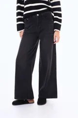 Jean de corte wide leg en color negro, con tiro medio y cierre frontal con botón y cremallera. Presenta un diseño de pernera ancha y recta, con bolsillos laterales y traseros.