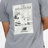 Remera New Balance de corte relajado, color gris, con mangas cortas y estampa frontal fotográfica en blanco y negro con la inscripción "The System" y el logo de la marca.