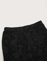 Pantalón de encaje negro con corte acampanado y cintura elástica.