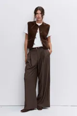 Chaleco de textura tipo corderito en color marrón chocolate, con cuello redondo, cierre frontal con botones y bolsillos laterales.