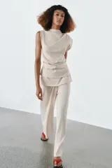 Pantalón de algodón compacto color beige, de tiro alto con cintura elástica y detalle de fajín y cordones.