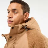 Campera con capucha color beige, con efecto borreguito en el cuerpo y las mangas, y detalles en tela lisa beige en los hombros y el pecho. Tiene cierre frontal y botones a presión.