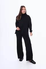 Buzo tejido de punto color negro, con cuello alto, manga larga y corte holgado con aberturas laterales en el ruedo.