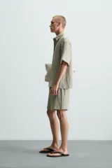 Bermuda negra de corte regular, confeccionada en tejido jacquard con efecto arrugado. Presenta cintura elástica ajustable con cordón blanco, bolsillos laterales y bolsillos traseros de vivo.