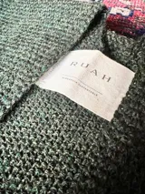 Ruana verde inglés de 100% baby alpaca, tejida en punto texturado. De forma rectangular y terminaciones con flecos cortos. Hilado de Perú, hecho en Uruguay.